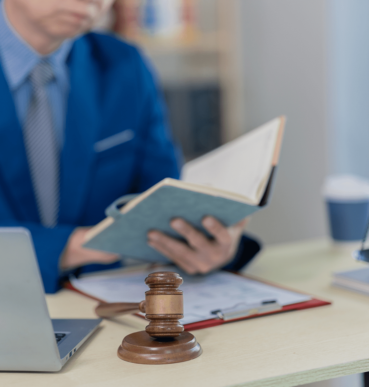 Gavel on desk with person reading book